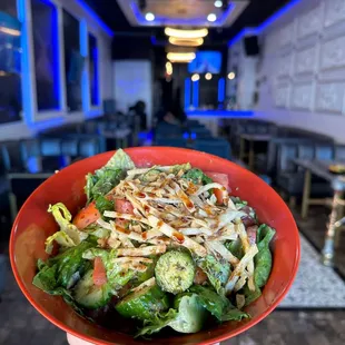 a hand holding a bowl of salad