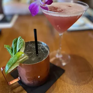 a cocktail in a copper mug with a purple flower