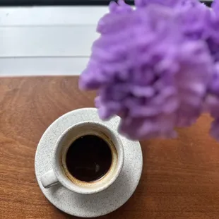 a cup of coffee and purple flowers