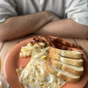a breakfast of eggs, toast, bacon, and toasted bread