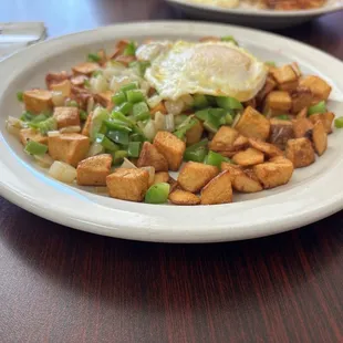 Breakfast potatoes with peppers and onions and an over-medium egg