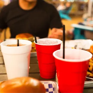 a man sitting at a table with a tray of food and cups of drink