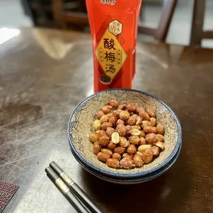 a bowl of peanuts and chopsticks