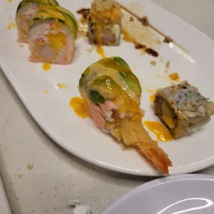 a plate of food with shrimp, shrimp, and other sushi
