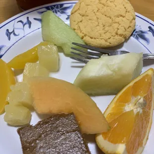 a plate of food with fruit and a cookie