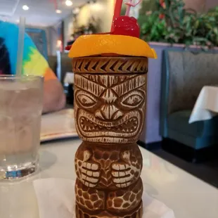 a tiki with a straw and a drink