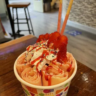 a cup of ice cream with sprinkles and strawberries