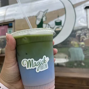 a hand holding a cup of matcha