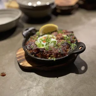 SISIG Crispy pork bits marinated in soy sauce and calamansi, mixed with onions, chili, and topped with an egg