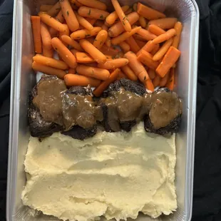 a meal of meat, mashed potatoes, carrots and gravy