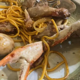 a plate of food with shrimp, crab legs, and noodles