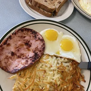 Ham and eggs with hash browns and raisin toast.