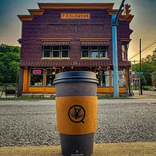 a coffee cup on a sidewalk in front of a coffee shop