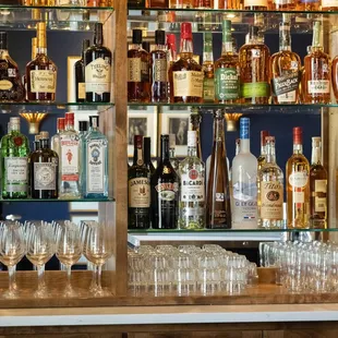 a shelf of liquor bottles and glasses