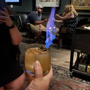 a person holding a glass with a blue flame in it