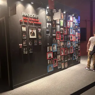 a man standing in front of a wall full of pictures