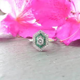 Art deco style diamond and emerald halo engagement ring.