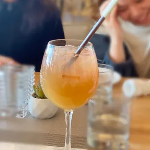 a woman sitting at a table with a drink