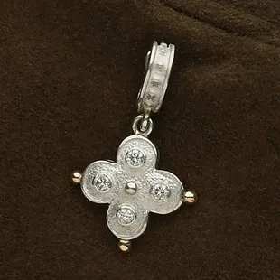 Beautiful sterling quatrefoil pendant with four diamonds and 18 karat god tips.The bale opens to fit over any necklace.