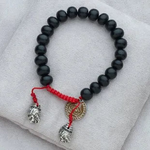 Beautiful ebony beads with solid, sterling silver lions&apos; head pulls on hand knotted, red silk.