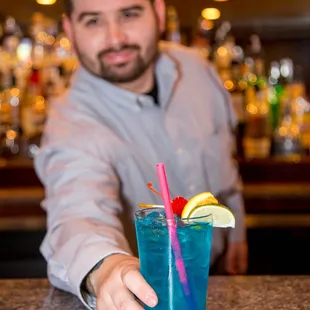 a bartender holding a blue drink