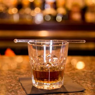 a glass of whiskey on a bar counter