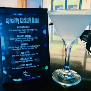 a cocktail glass and menu on a table