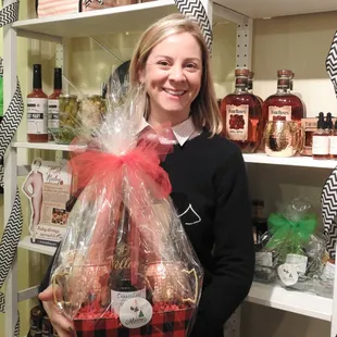 a woman holding a basket of wine and chocolates