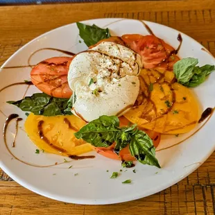 Tomato caprese salad with burrata, heirloom tomato slices, and balsalmic glaze drizzle.