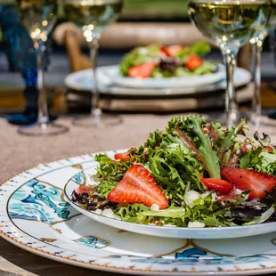 a plate of salad with strawberries and lettuce