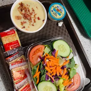 a salad, soup, and crackers on a tray