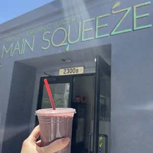 a hand holding up a pink smoothie