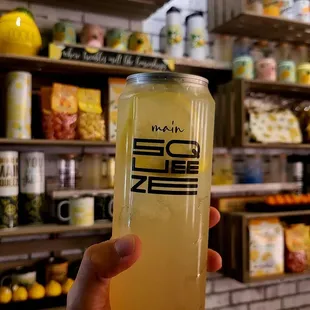 a person holding a can of lemonade