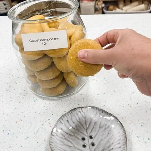 a person picking a donut from a glass jar