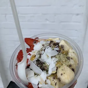a hand holding a smoothie with strawberries, bananas, chocolate chips, and strawberries