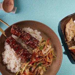 ows a plate of rice, meat, and vegetables