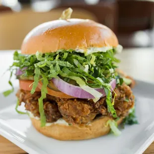 ows a burger with meat, lettuce, tomato, onion, and