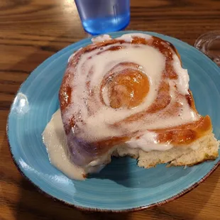 a cinnamon roll with icing and a glass of water
