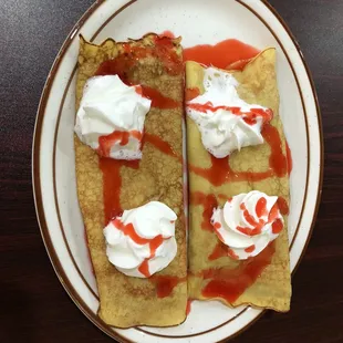 a plate of crepes with whipped cream and ketchup
