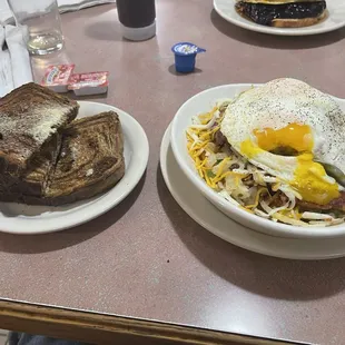 Corned Beef hash skillet with two eggs over easy and 2 pieces of marble rye toast with butter.