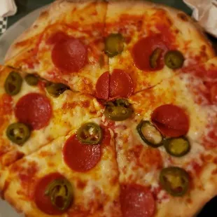 Person 9&apos; pizza with pepperoni and jalapeños