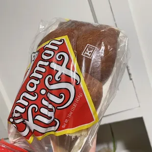 a person holding a loaf of bread wrapped in plastic