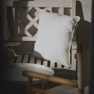 a white pillow on a wooden bench