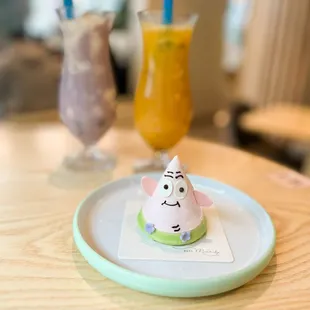 a cupcake on a plate with a drink in the background