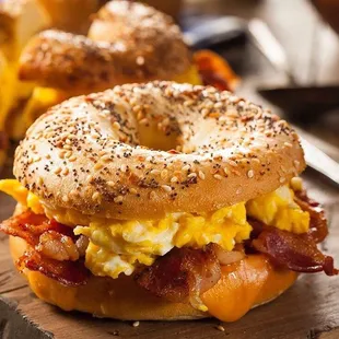 a bagel sandwich with eggs and bacon