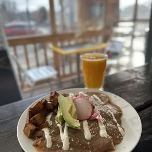 a plate of enchilada and a glass of orange juice