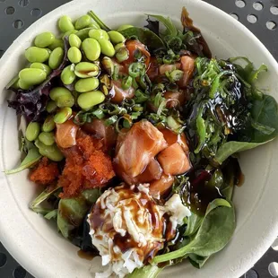 Large bowl with salad base, salmon poke, seaweed salad, edamame, crab salad, and masago.