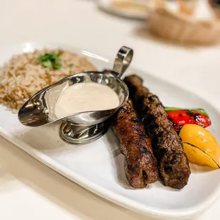 a plate of meat, rice, and sauce