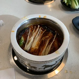 Mala soup base with enoki mushrooms