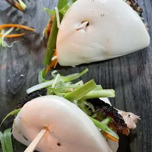 Bao (Vietnamese-inspired bun) with juicy pork inside, garnished with vegetables.